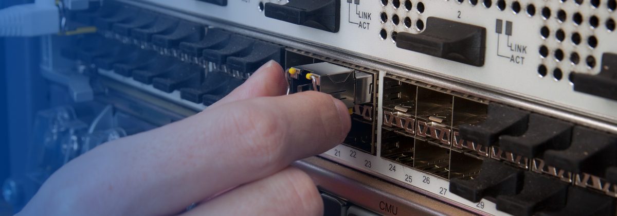 Technician inserting an SFP module in network hardware as part of secure asset recovery.